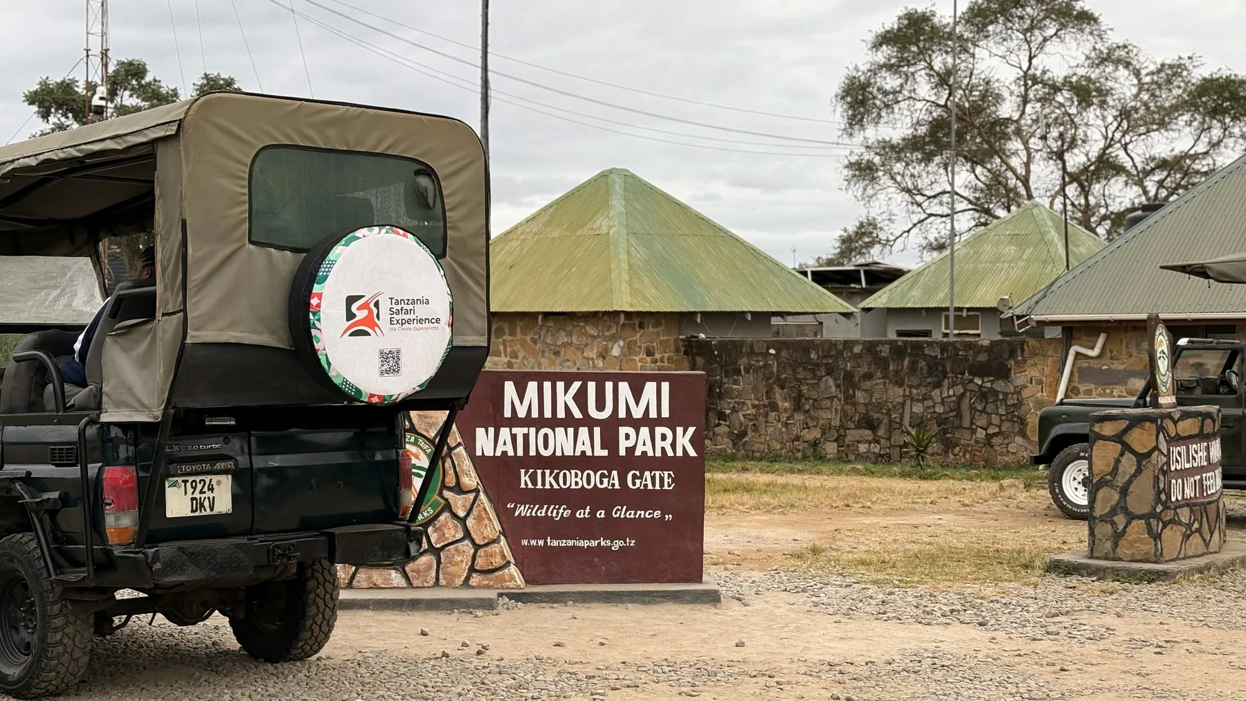 Safari jeep beside the Mikumi National Park entrance sign
